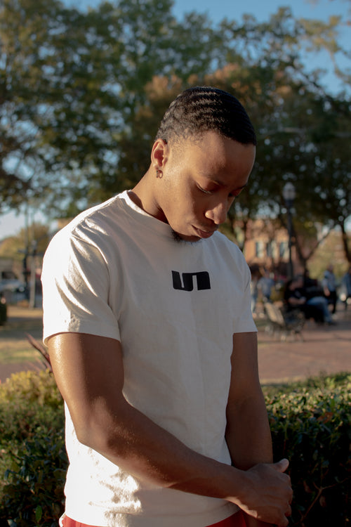 A model wearing the UNLONELY Logo Tee in the Cream colorway.